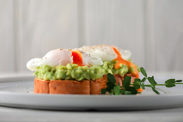 European breakfast. Toasted bread with avocado, poached egg and fruit juice on a white wooden table. healthy diet food