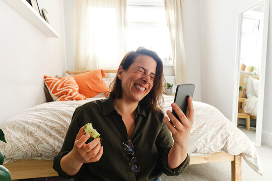 Happy woman doing video call through smart phone at home
