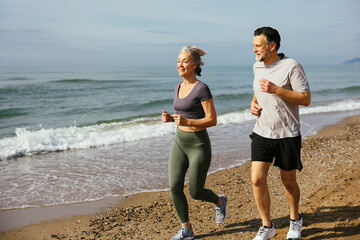 Mature couple jogging together at sunny day