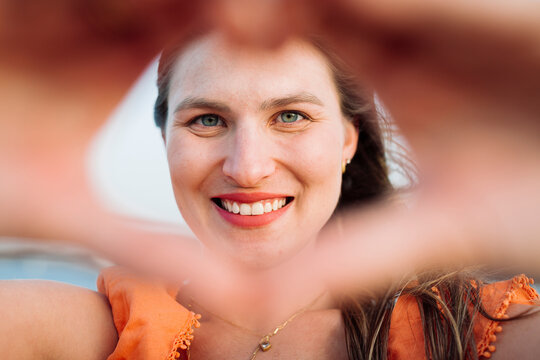 Smiling woman making heart shape with hands
