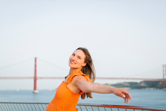Smiling pregnant woman with arm outstretched near railing