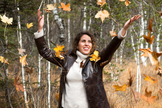 Happy woman playing with autumn leaves at forest