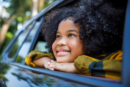 Smiling girl day dreaming and leaning on car window