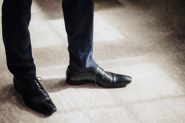Legs of businessman wearing black formal shoes standing in factory