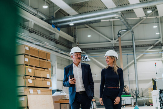 Senior businessman discussing with smiling colleague in carpentry factory