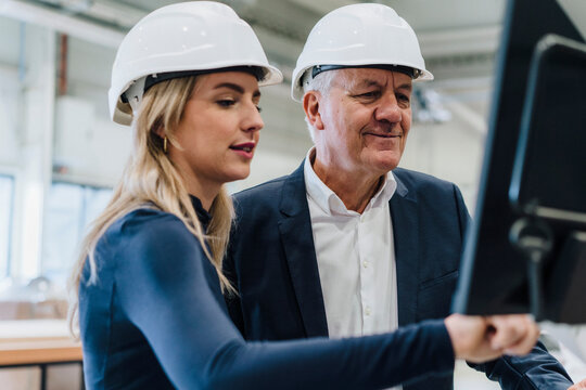 Businesswoman and businessman discussing over computer in factory