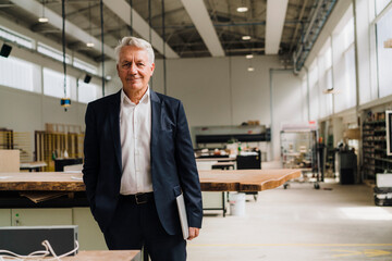 Smiling senior businessman standing in carpentry factory