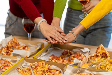 Colleagues having lunch at pizza party and eating assorted pizzas and drinking red wine on rustic wooden table celebrating fast food lunch