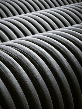 Vertical image of large black plastic corrugated pipes for water supply. Reconstruction of the pipeline and sewerage in the city.