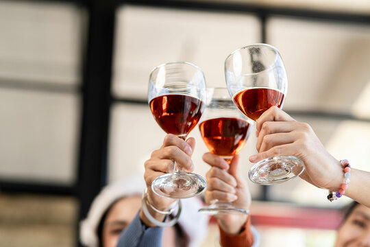 People toasting glasses of wine on the summer terrace of a cafe or restaurant with a group of friends in low light toasting wine.