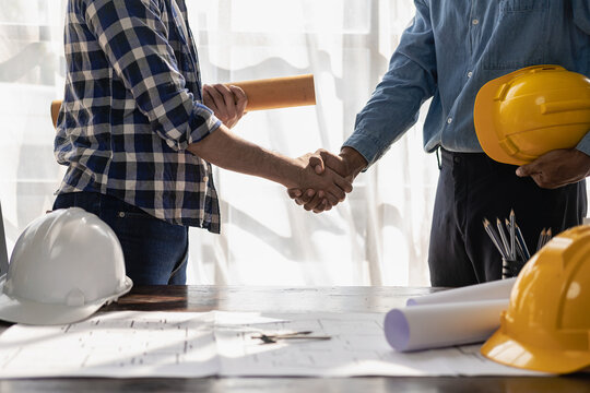 Construction Workers Holding Helmets And Vests Are Shaking Hands. Real Estate Concept Architect Shaking Hands With Engineer Or Builder Planning And Successful Meetings