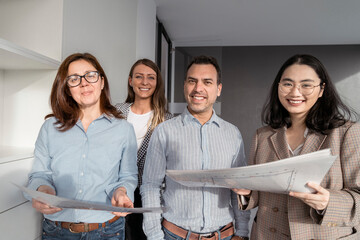 Confident business people standing in office holding architectural plans