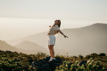Carefree woman standing with arms outstretched on mountain