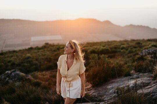 Smiling woman strolling on mountain at sunset