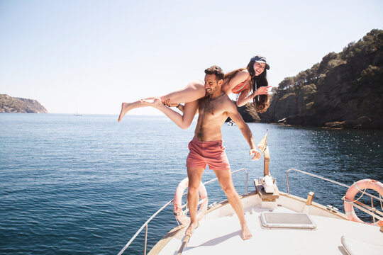 Shirtless man having fun with girlfriend on yacht at vacation