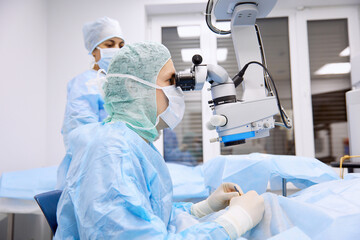 Surgeon performing eye surgery with microscope in operating room