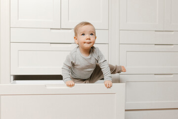 Baby boy coming out of wardrobe drawer at home