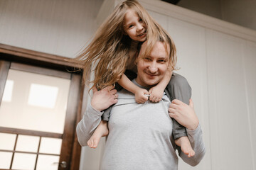 Smiling father carrying daughter on shoulders at home