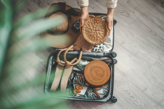 Top View Of Woman Packing Suitcase With Hat, Camera And Bag For Travel