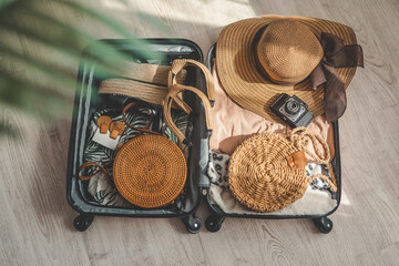 Vacation and travel concept. Suitcase, hat, bag and sunglasses on wooden floor