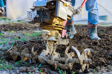 Farmer uses motor cultivator to plowing ground in garden using tiller block for plow