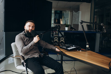 Young smiling radio host talking into a microphone and broadcasting in the studio, entertainment...