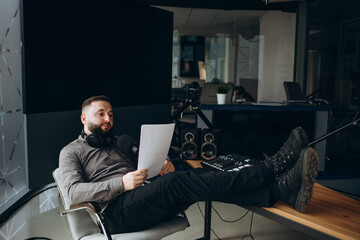 Radio anchorman hosts the evening talk-show. Young man working as a radio anchorman sitting at the...