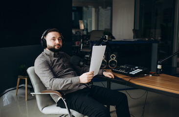 Radio anchorman hosts the evening talk-show. Young man working as a radio anchorman sitting at the...