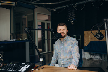 Portrait of smiling hispanic male radio presenter with clipboard hosting a show at radio station