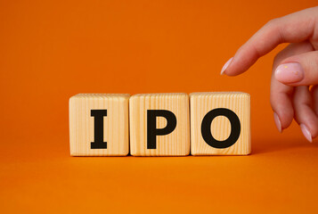 IPO- Initial Public Offering symbol. Concept word IPO on wooden cubes. Businessman hand. Beautiful orange background. Business and IPO concept. Copy space.