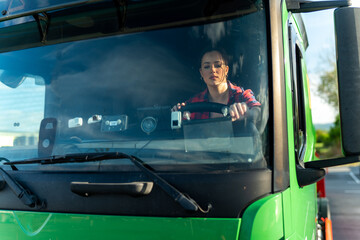Portrait of a woman sitting behind the wheel of a truck, view through the windshield