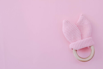 Baby rattle toy. Children's knitted rabbit on a pink background for a girl. Handmade rattle for a newborn.