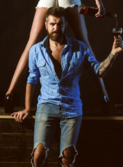 Couple playing with sexy legs. Handsome man holding womans leg in elegant shoes. Sexy couple tasting wine.