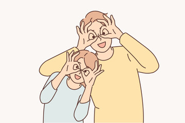 Happy father and daughter make funny faces to have fun putting fingers to eyes instead of glasses