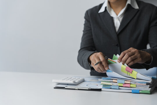 Businesswoman hands working in piles of paper documents looking for market and financial data report on desk, business report paper, stack of papers. Unfinished folder sheet business idea.