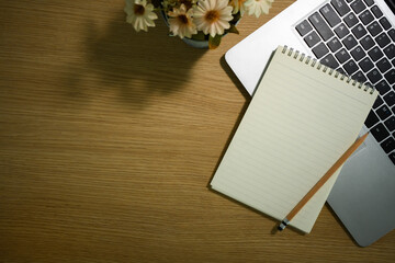 Naklejka premium Blank spiral notepad, pencil and laptop computer in wooden working desk. Top view with copy space