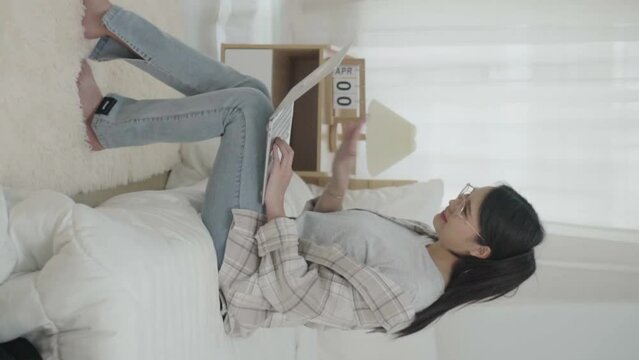 Asian freelance business woman using laptop 
 video call  freind in bed at home.