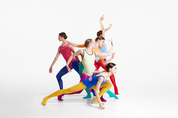 Young girls, ballet dancers in colorful tights and bodysuits training, dancing against grey studio background. Concept of beauty, creativity, classic dance style, elegance, contemporary art