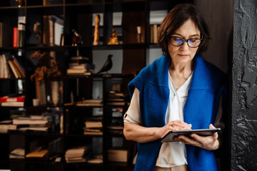 Mature woman using digital tablet while working in office
