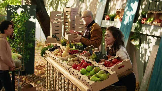 Female farmer giving free apple samples to clients for food tasting, enjoying bio products sampling at local greenmarket. Woman cutting slices of fruits to give to customers, business owner.