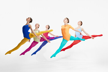 Jumping, flying. Tender female ballet dancers in colorful tights and bodysuits, dancing against grey studio background. Concept of beauty, creativity, classic dance style, elegance, contemporary art