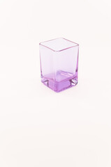 immagine con vista dall'alto di elegante dal disegno moderno bicchiere vuoto  in cristallo violetto su una superficie bianca