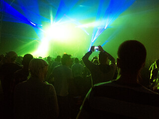 Fototapeta na wymiar Silhouette of crowd facing illuminated stage at music festival