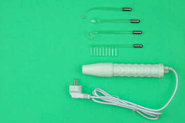 Darsonval for body and hair care on a green background. Therapy for skin. Darsonvalization. Top view. Copy space.