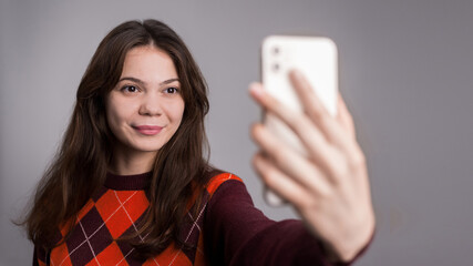 Young smiling woman filming herself on the phone