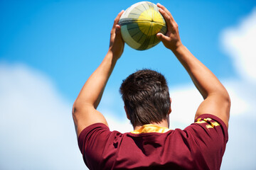 Rugby, sports and man throw ball outdoor on a pitch with blue sky for goal. Headshot of male athlete person playing in sport competition, game or training for fitness, workout or exercise from behind