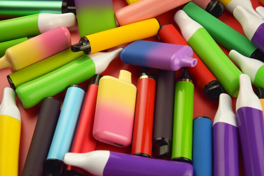 Set of multicolor disposable electronic cigarettes on a red background.