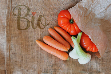 Nourriture bio dans un sachet craft sur toile de jute tomates carottes oignons