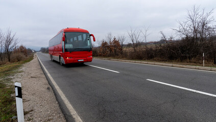 Fototapeta na wymiar Red bus on a mountain road. Travel through the mountainous regions of the desert. tourist trip. Touristic Red bus on highway. Red bus in the road of Serbia and green forest at sides.