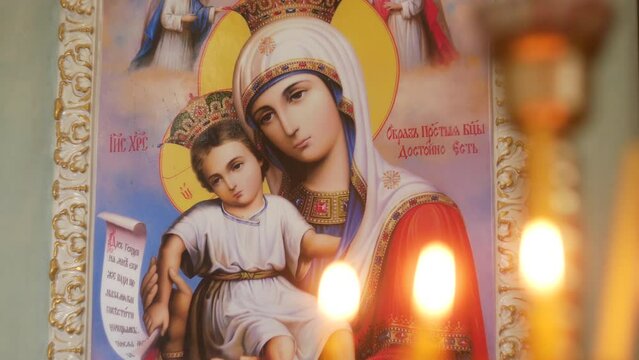 Beautiful Orthodox Church. Icons of the Mother of God on the walls. Candles burn in lamps. A place for prayer to God and believers. Bible and cross in hand.